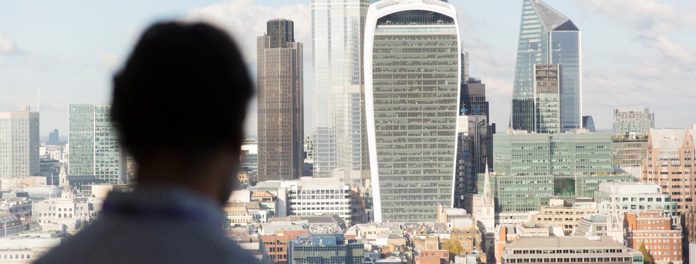 A person looks out over the City of London skyline, including 20 Fenchurch Street and Tower 42.