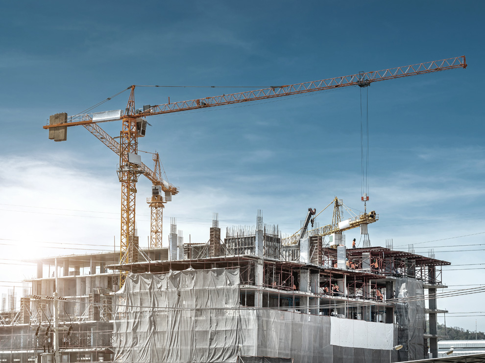 Panorama view at workers working on large construction sites with many cranes