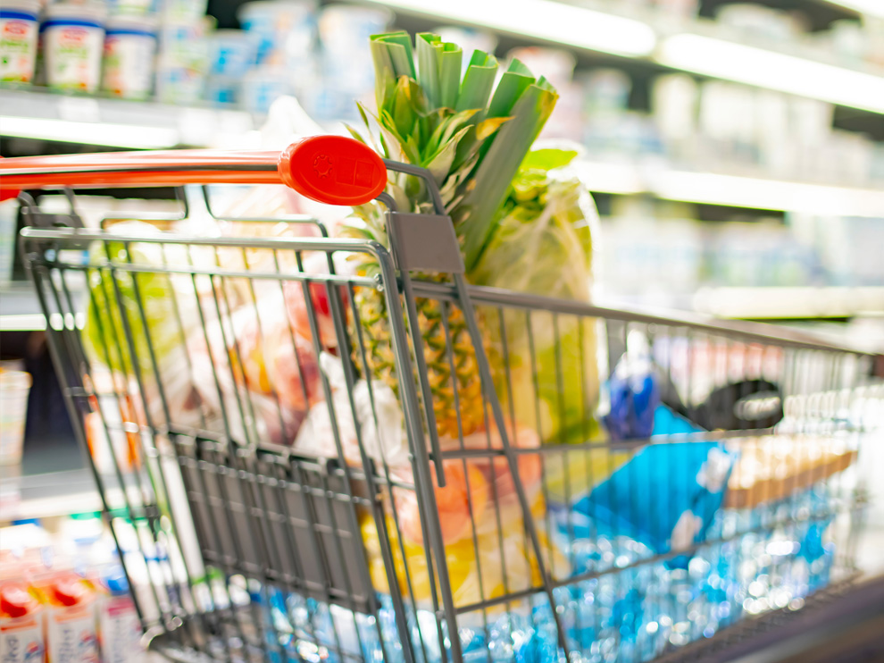 A shopping cart with grocery products in a supermarket