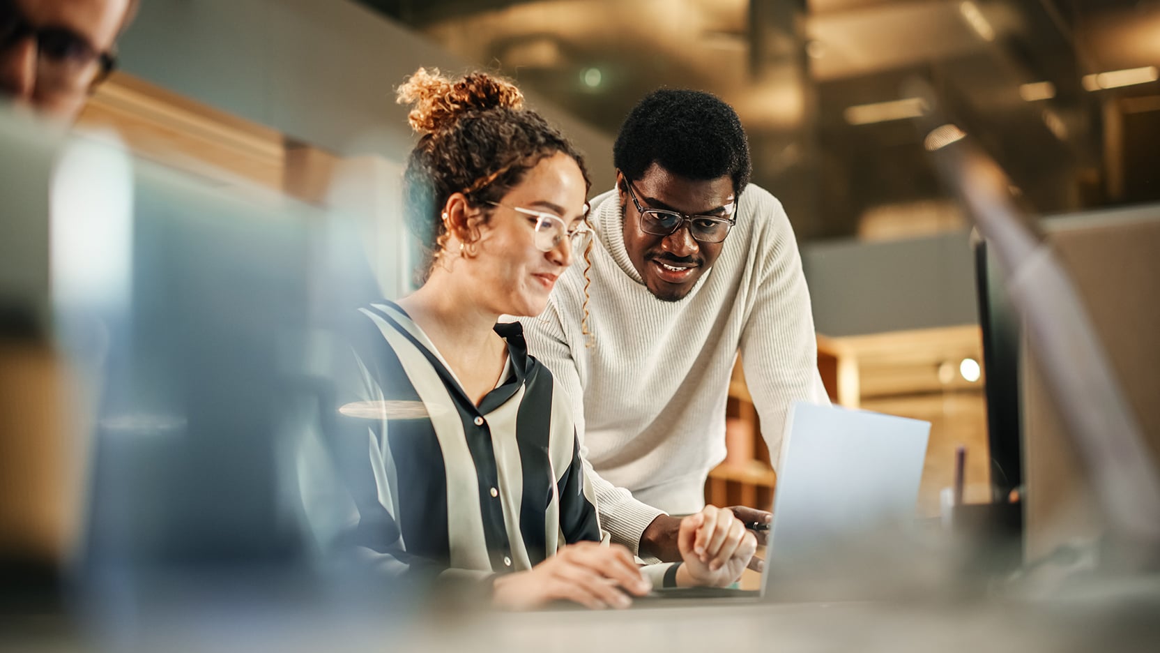 Two professionals collaborating at a laptop in a modern office, representing CBRE's AI-powered Next Action Engine helping real estate teams uncover hidden portfolio savings