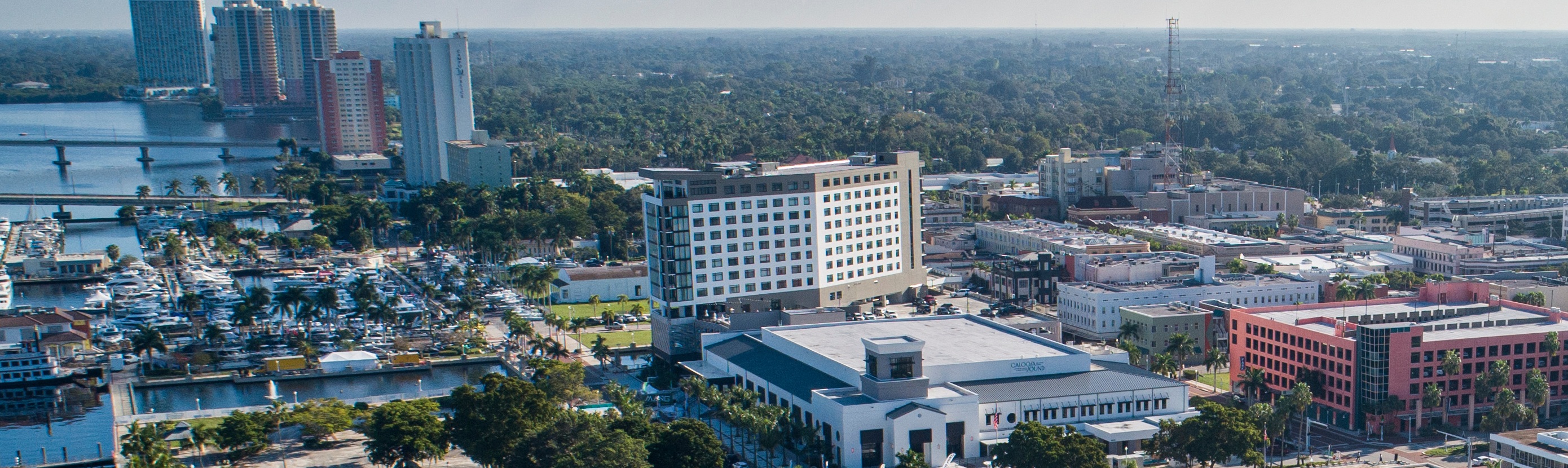 Aerial view of downtown Fort Myers waterfront showing office buildings, marina, bridge, and surrounding urban commercial district.