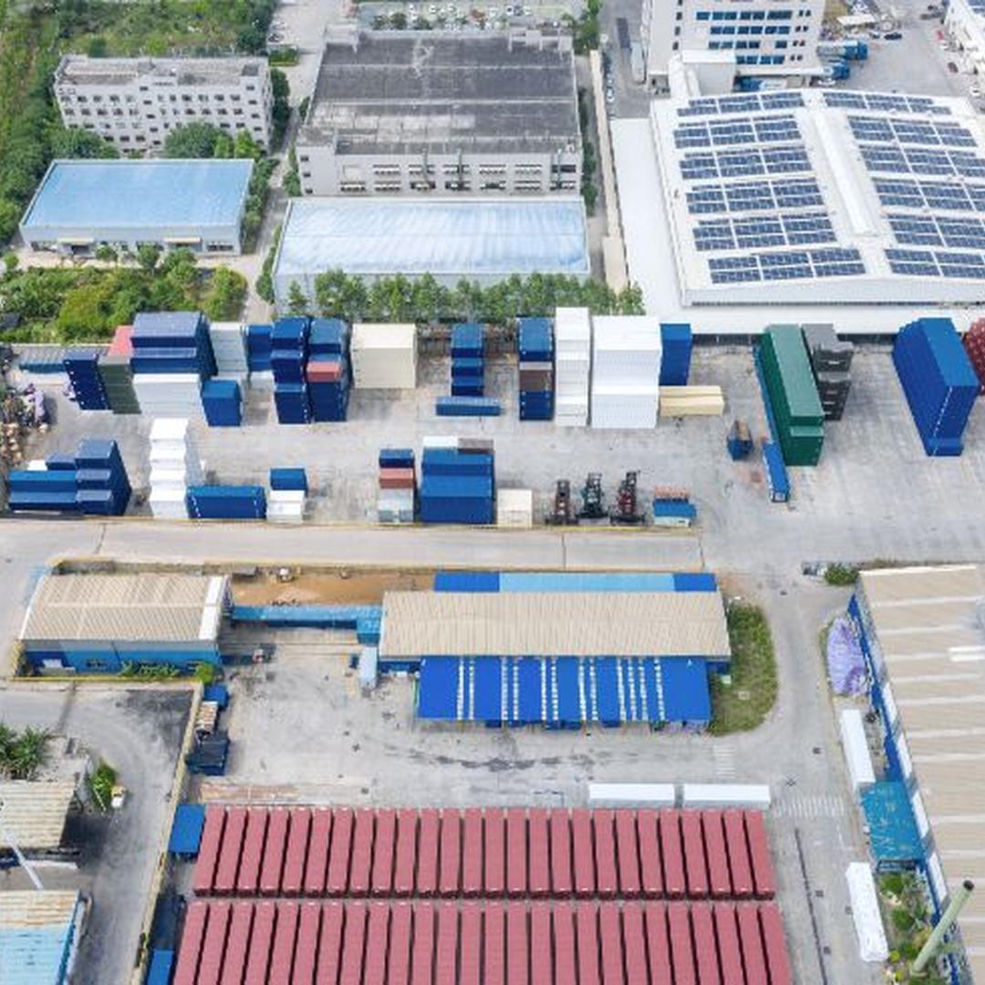 Industrial outdoor storage facility with organized containers and equipment under clear sky.