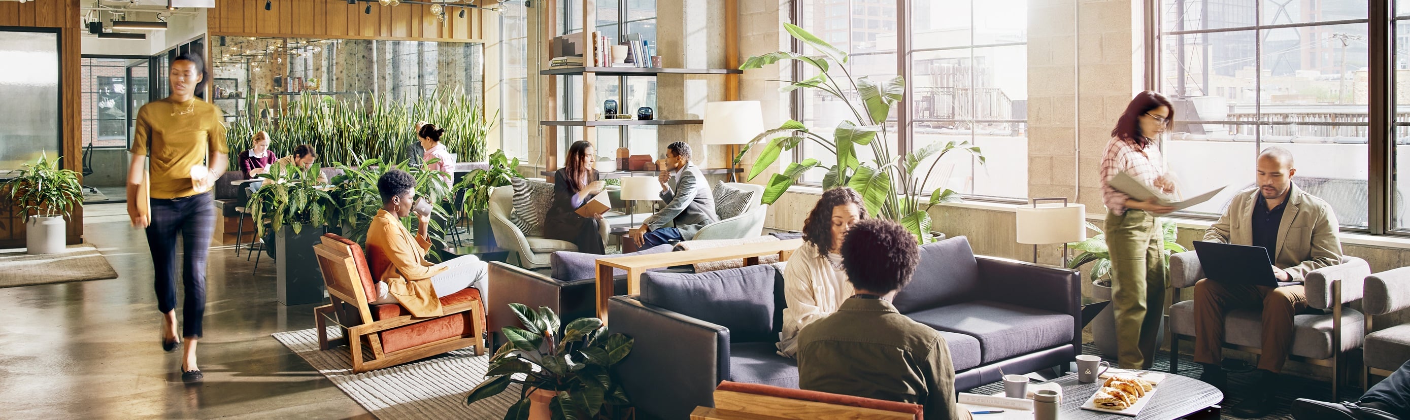 Professionals working and collaborating in a light-filled, plant-filled modern office common area