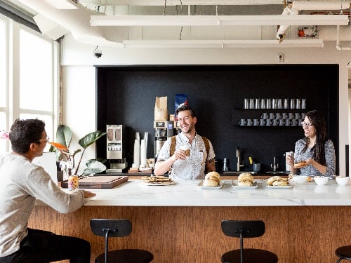 Employees socializing at a modern workplace café bar with coffee service and fresh food