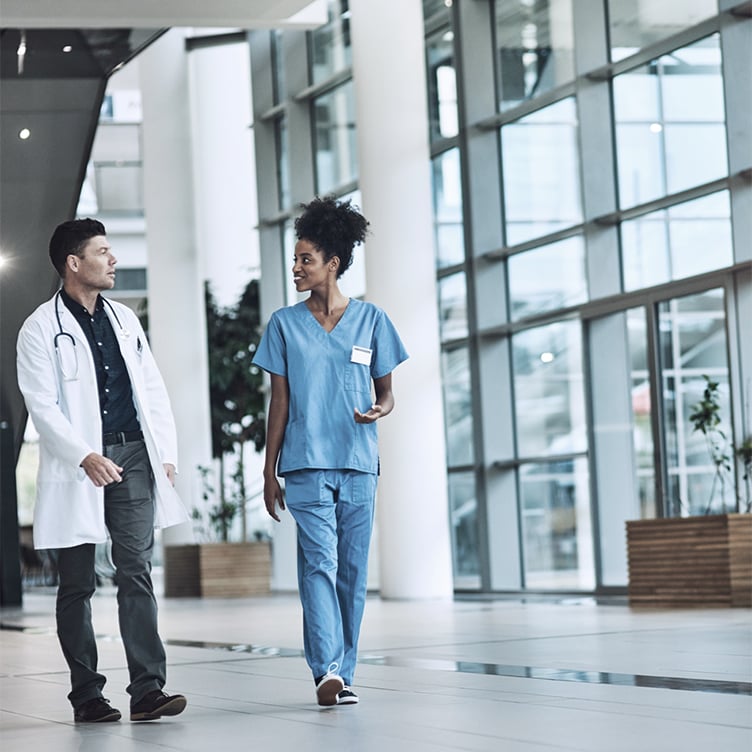 Healthcare professionals walking through a modern hospital hallway discussing patient care and collaboration