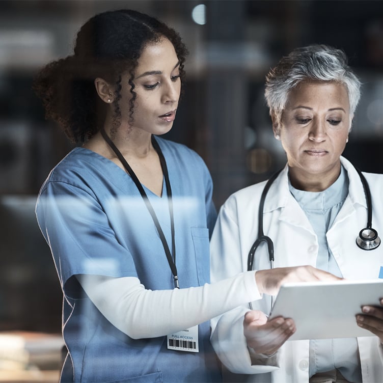 Healthcare professionals reviewing patient information on a tablet in a clinical setting