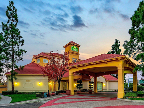Exterior of a La Quinta Inn & Suites property at dusk, part of a 685-key corporate-owned portfolio sold across multiple states by CBRE
