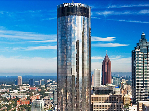 Aerial view of the Westin Peachtree Plaza cylindrical glass skyscraper rising above the Atlanta, Georgia skyline, a 1,073-key full-service hotel sold by CBRE