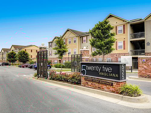 Exterior view of 5 Twenty Five Angliana student housing community with monument sign, gated entry, and apartment buildings