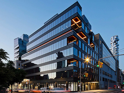Twilight exterior of 15 Laight Street in Tribeca, NYC featuring a dark glass curtainwall office building with illuminated orange accent panels on upper floors.