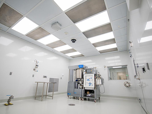 Bright pharmaceutical cleanroom with Millipore bioprocessing equipment under HEPA-filtered ceiling panels, reflecting CBRE life sciences facility capabilities.