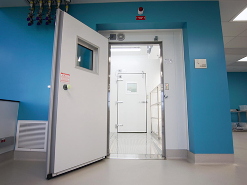 Open cleanroom door revealing a temperature-controlled cold storage room with insulated access, supporting CBRE life sciences facility management.