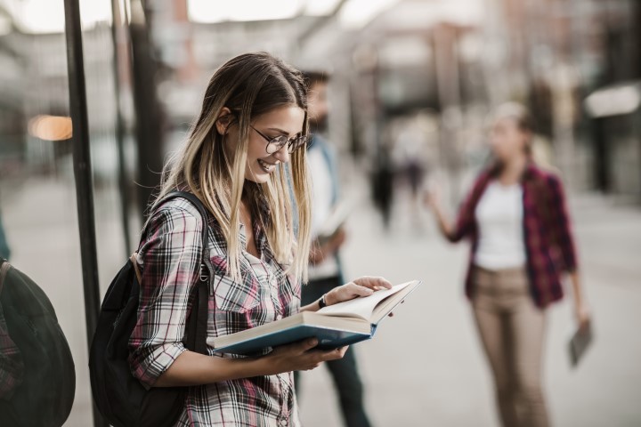 Étudiant ou jeune professionnel appréciant la vie urbaine à proximité d'une zone commerciale.