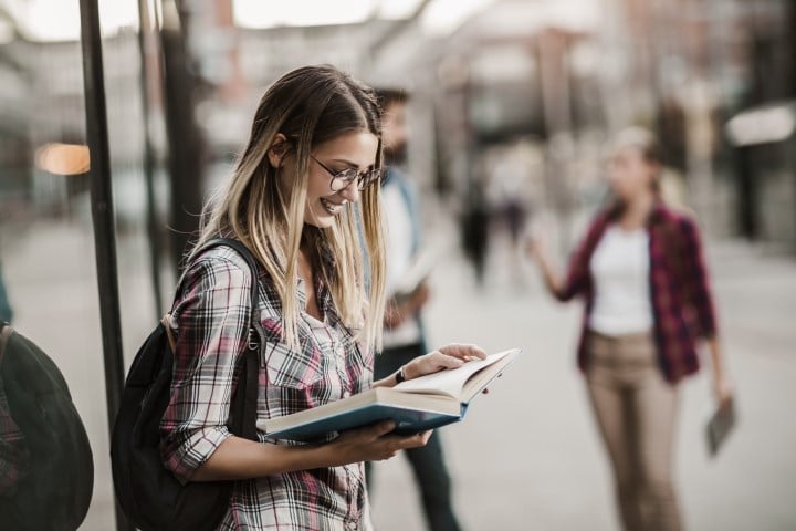 Étudiant ou jeune professionnel appréciant la vie urbaine à proximité d'une zone commerciale.