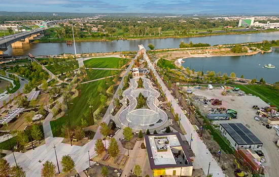 Aerial view of Omaha riverfront park with landscaped green spaces, walking paths, and Missouri River in the background.