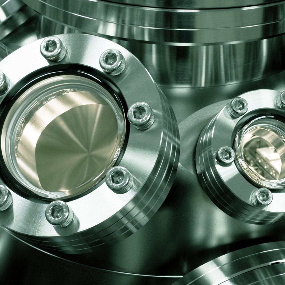 Close-up of polished stainless steel optical flanges with glass viewports and bolts