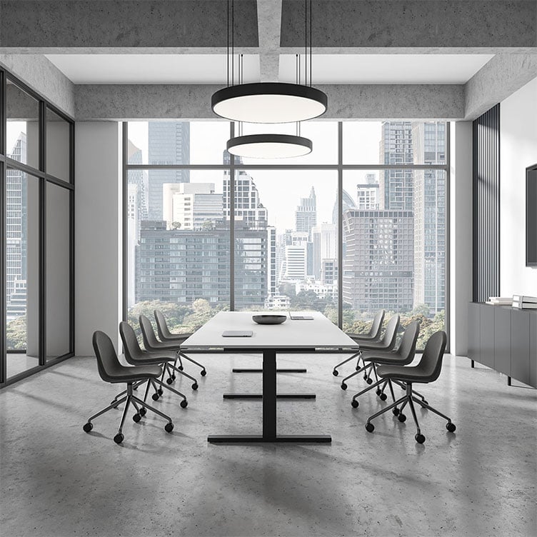 Empty modern conference room with a white table, grey chairs, concrete floors, circular pendant lights, and floor-to-ceiling windows overlooking a city skyline.