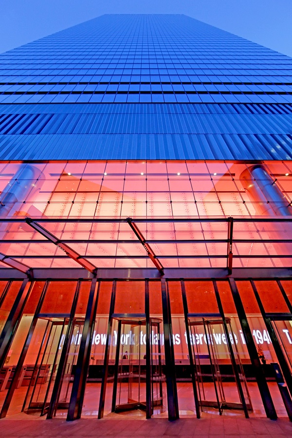 Jenny Holzer's For 7 World Trade LED text artwork scrolling across the illuminated red glass lobby entrance of 7 World Trade Center in New York City.