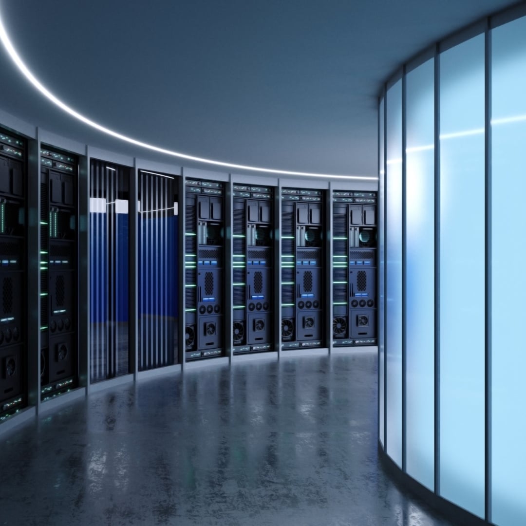 A data centre with rows of servers lining a curved wall, illuminated by cool blue and green lights, and a reflective floor.