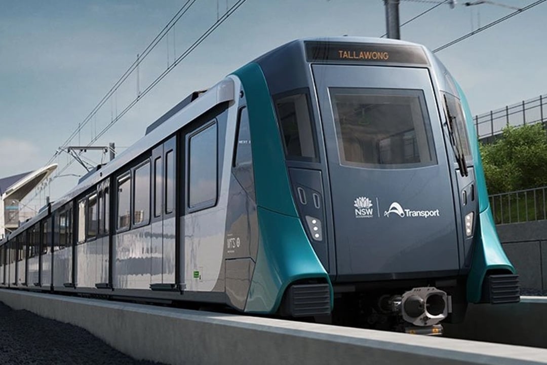 Sydney Metro train travelling along an elevated rail line with overhead wires and the destination sign showing Tallawong.