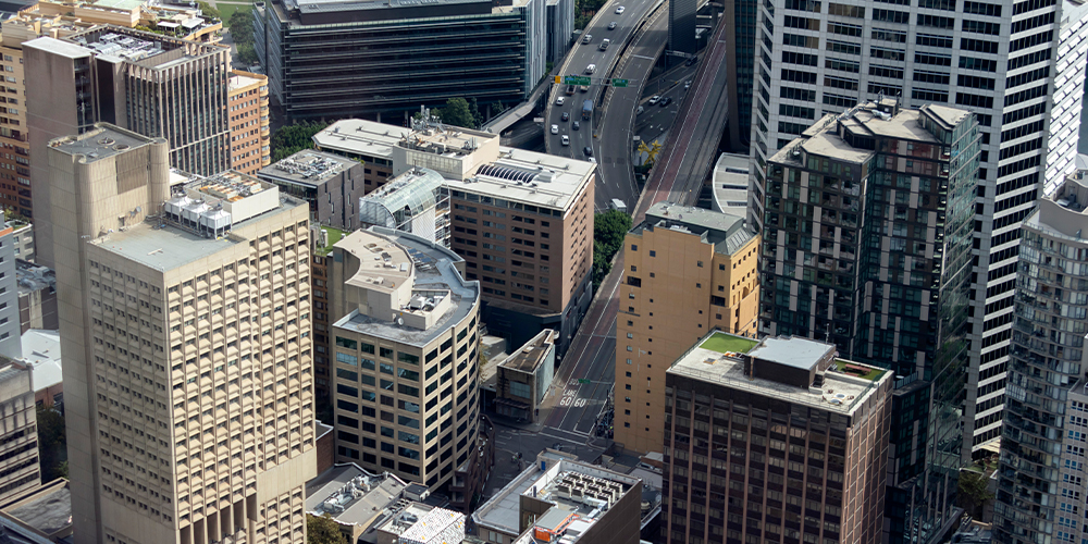 Aerial view of a dense city centre featuring a mix of office towers, residential buildings and major roads weaving through the urban landscape.