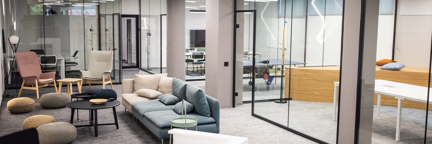Modern office lounge with collaborative seating, glass meeting rooms, and flexible workspace amenities.