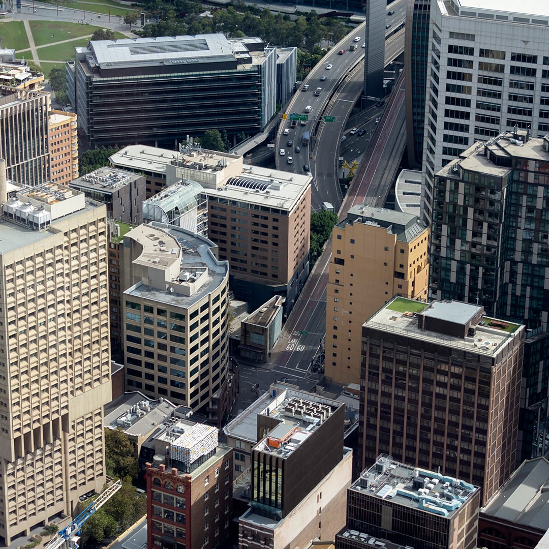 Aerial view of a dense city centre featuring a mix of office towers, residential buildings and major roads weaving through the urban landscape.