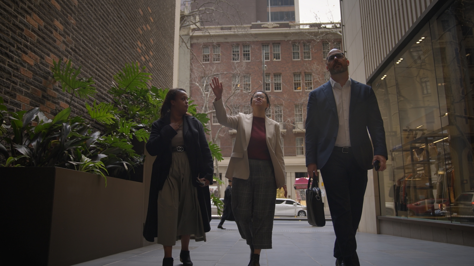 Three businesspeople walk down a city street.