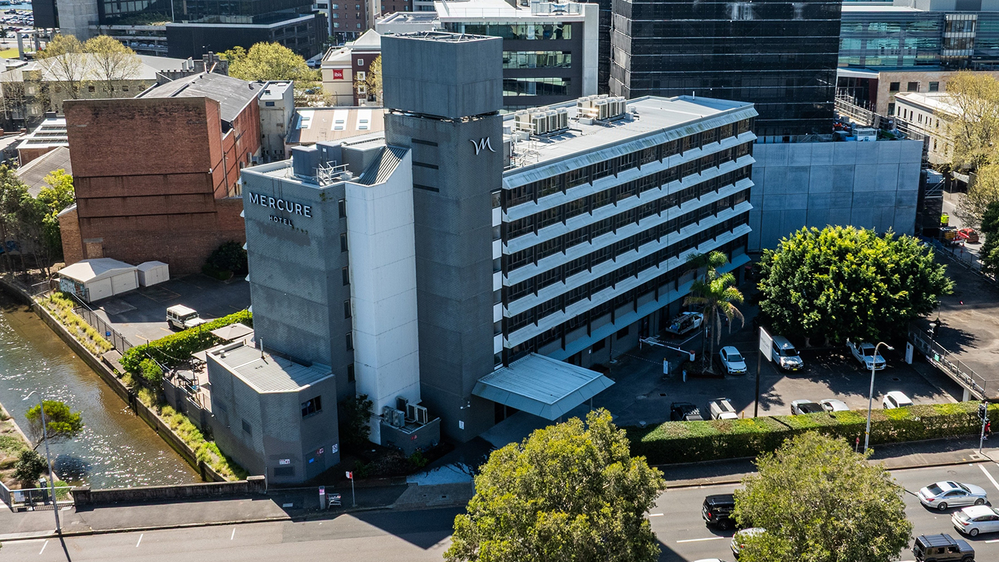 Mid-rise hotel property, Mercure Newcastle, positioned alongside a waterfront corridor within a commercial city district.