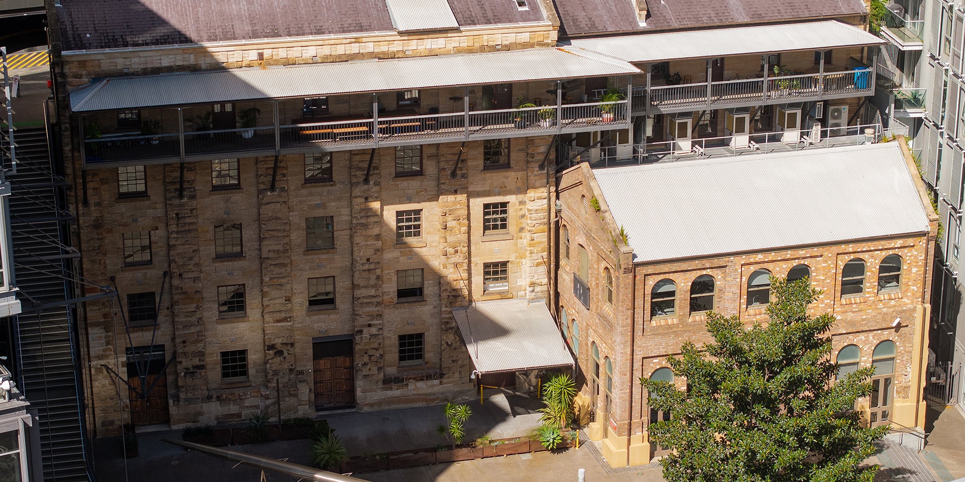 Restored heritage warehouse building with sandstone and brick façades, situated within a revitalised mixed-use waterfront precinct. 