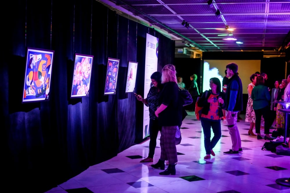 Attendees enjoy an art exhibit bathed in purple and green light at the Flow and Glow event.