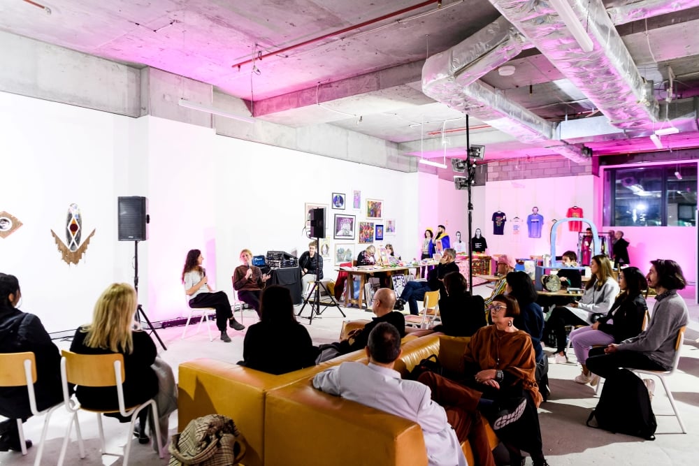 Attendees gather in a brightly lit room with pink accents, enjoying an engaging panel discussion at the Flow and Glow event.
