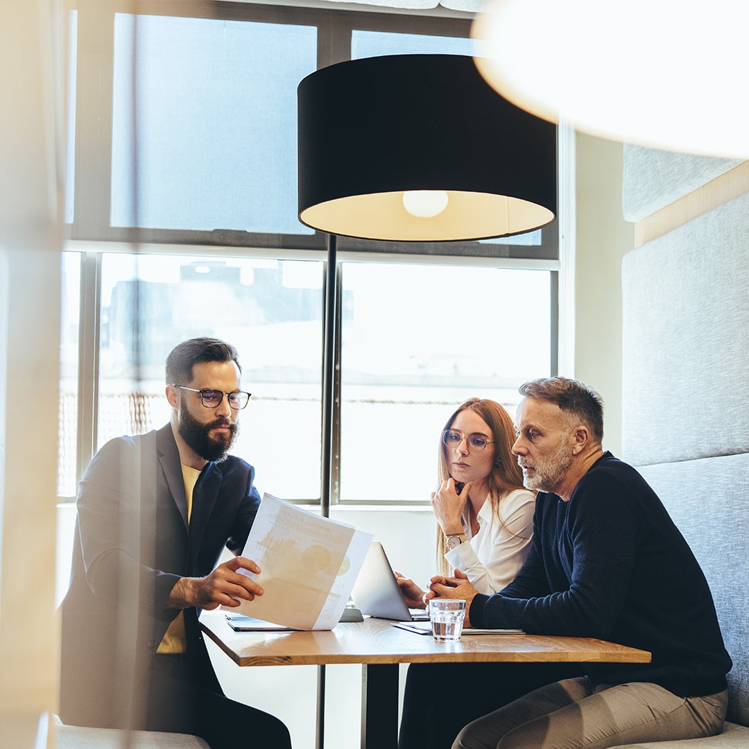 The image shows colleagues discussing a project in a co-working space.