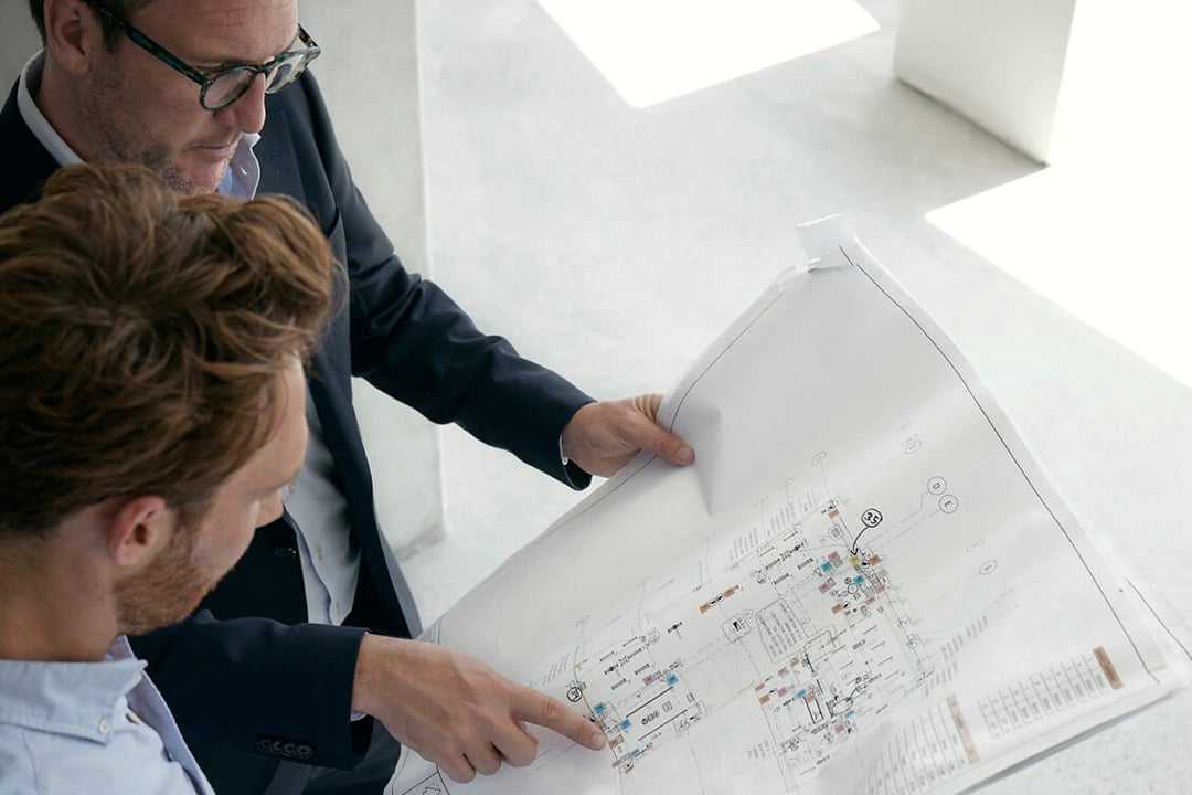 Two businesspeople review blueprints for Wilmac Altona North, a reimagined industrial park prioritising community and well-being.