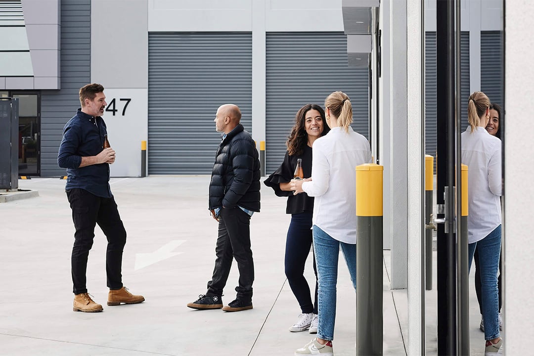 A group of people relax outside contemporary warehouse units at the Wilmac Altona North industrial park, showcasing its blend of workspace and amenity.