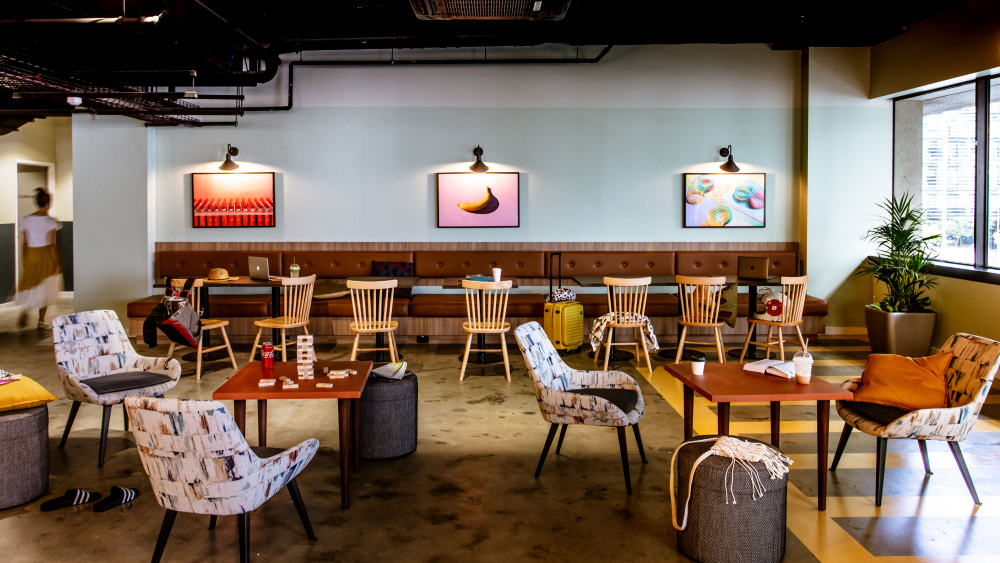 The common room at Hostel G Perth has a relaxed atmosphere with colourful artwork, comfortable seating, and games.