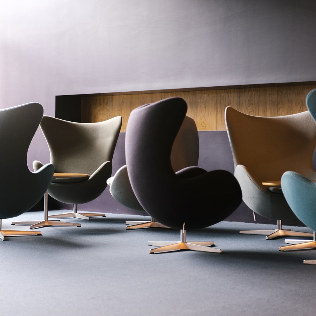 Modern curved chairs in various colors arranged in a semi-circle on a carpeted floor with wood-paneled walls.