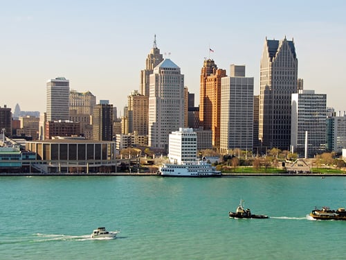 The vibrant Detroit, Michigan skyline with prominent commercial buildings along the Detroit River, showcasing a dynamic urban real estate market.