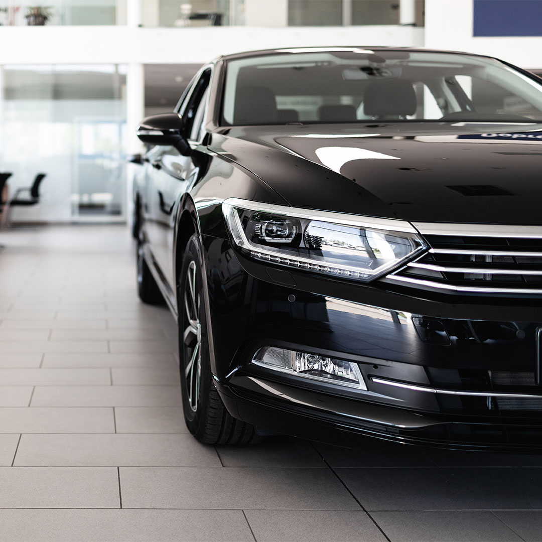 A black car showcased inside a modern dealership showroom.