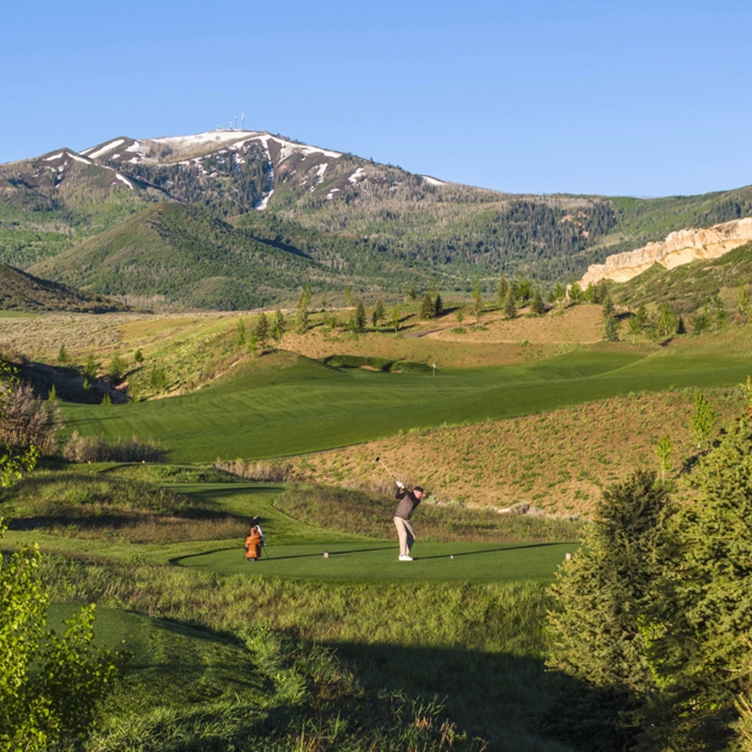 Wohali Utah golf course tee shot with panoramic Wasatch Mountain views, snow-capped peaks, and lush fairways nestled in a scenic alpine valley