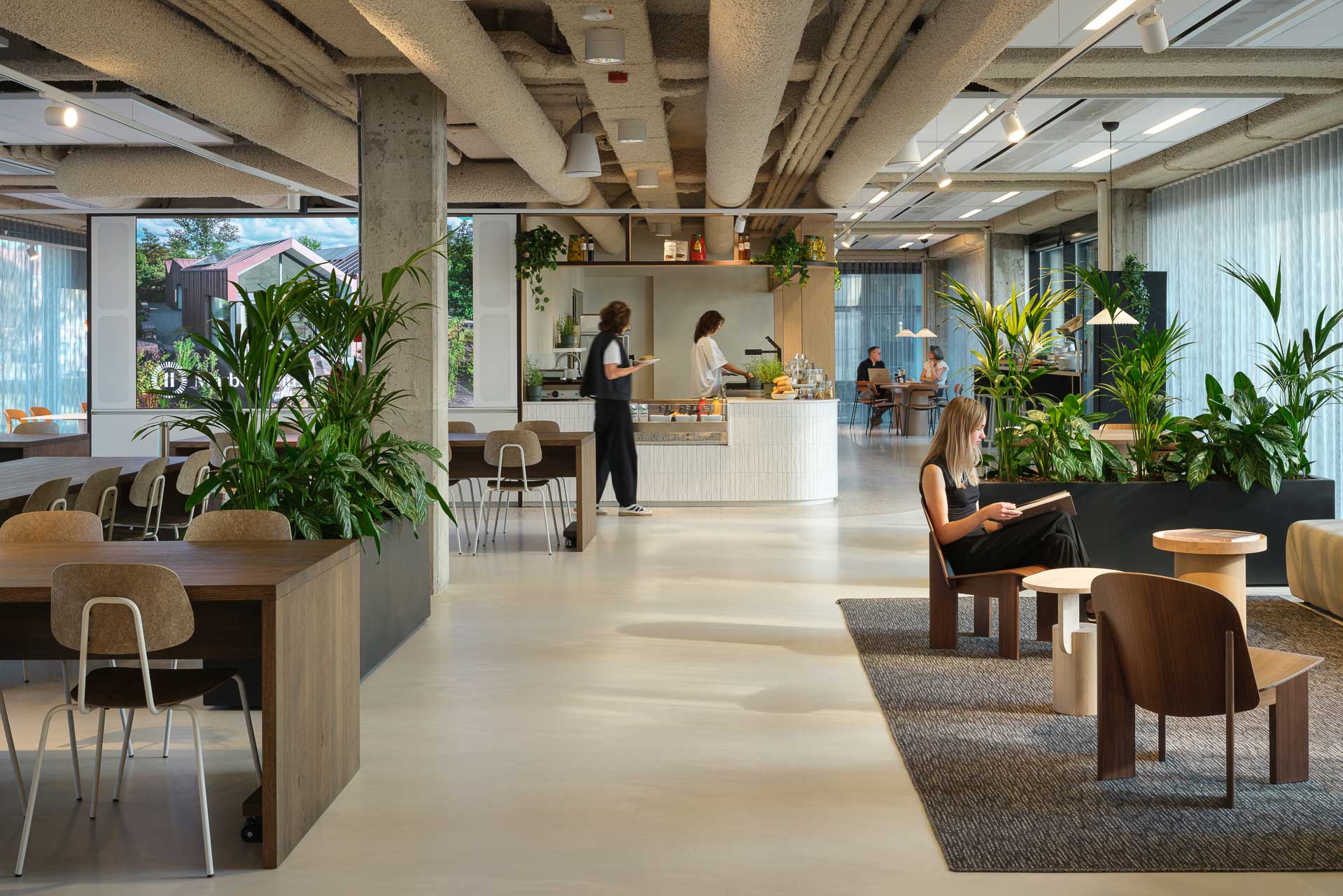 An open-plan office with various seating areas on both sides and a few people walking around in the middle.