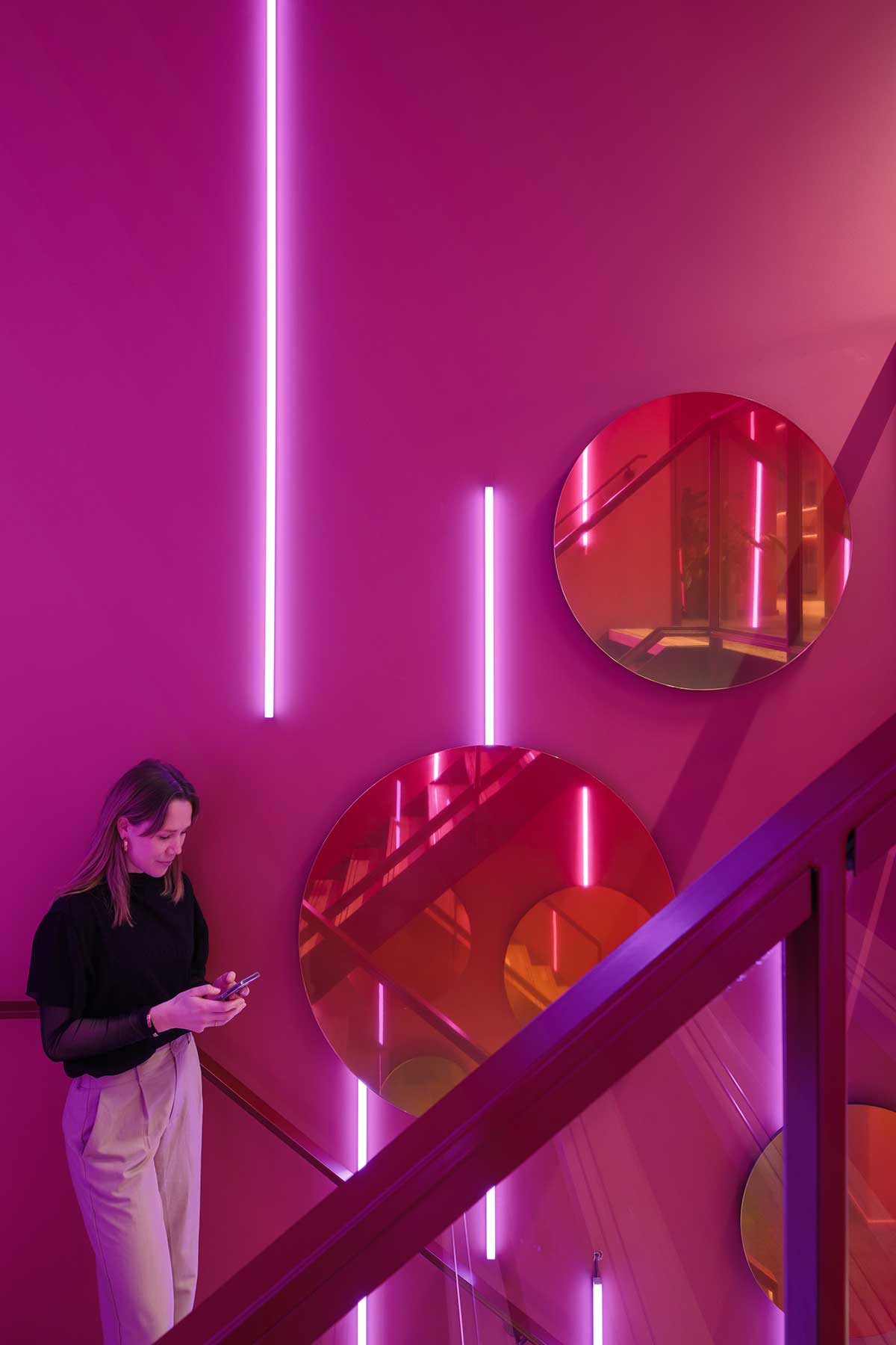 Futuristic stairwell with pink-purple LED lines and reflective round panels.