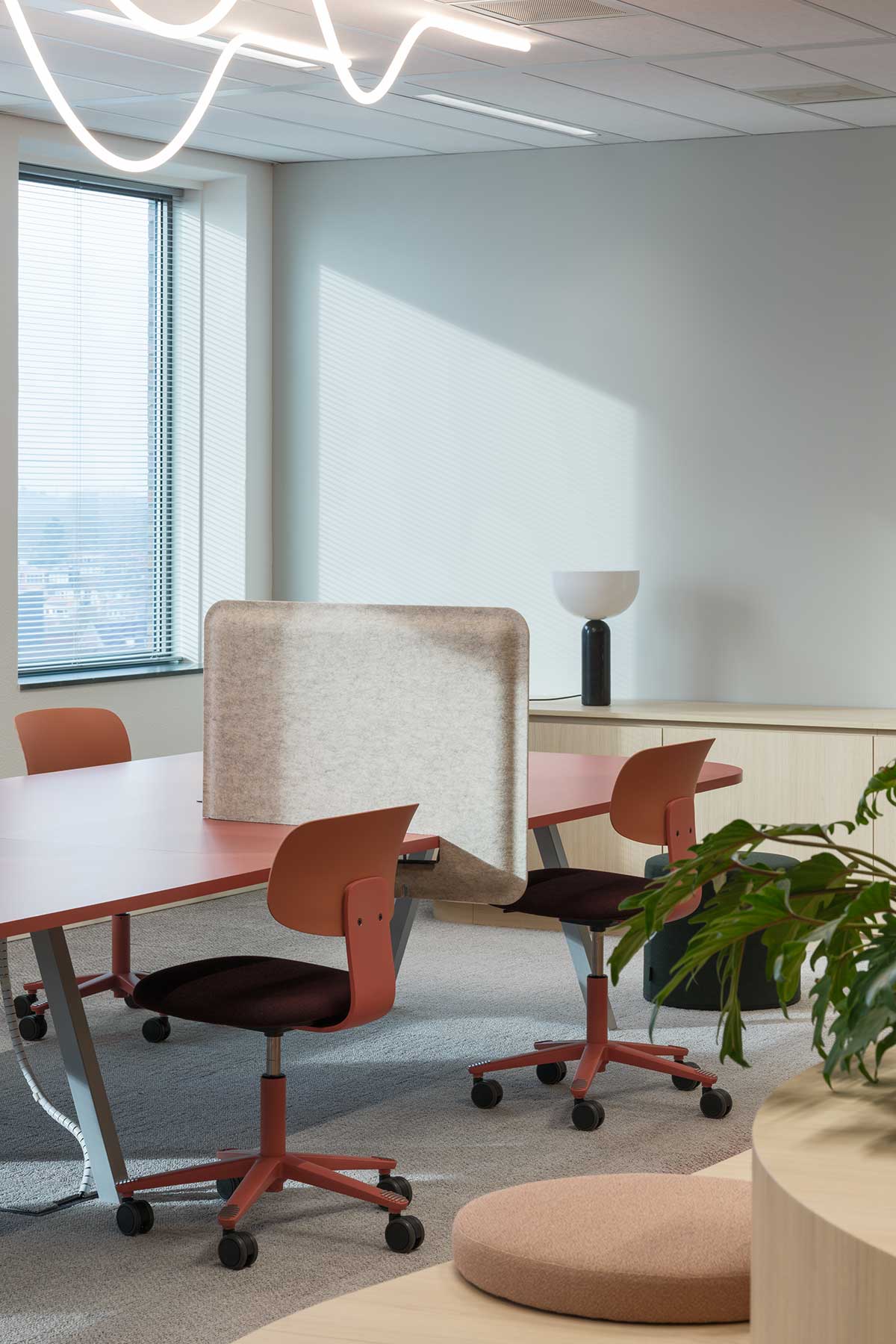 Modern office space with shared work table, felt privacy screen, ergonomic office chairs and plenty of natural light.