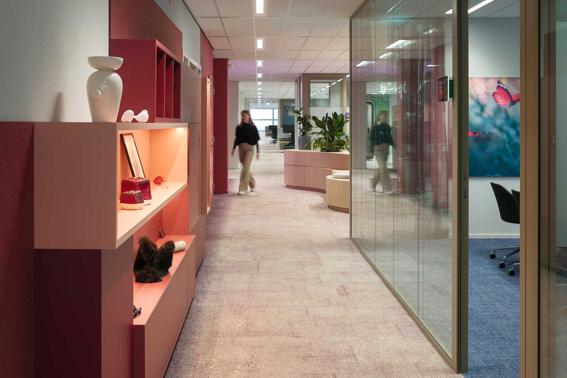 Modern office hall with decorative shelves, glass meeting rooms, warm colours and contemporary décor.