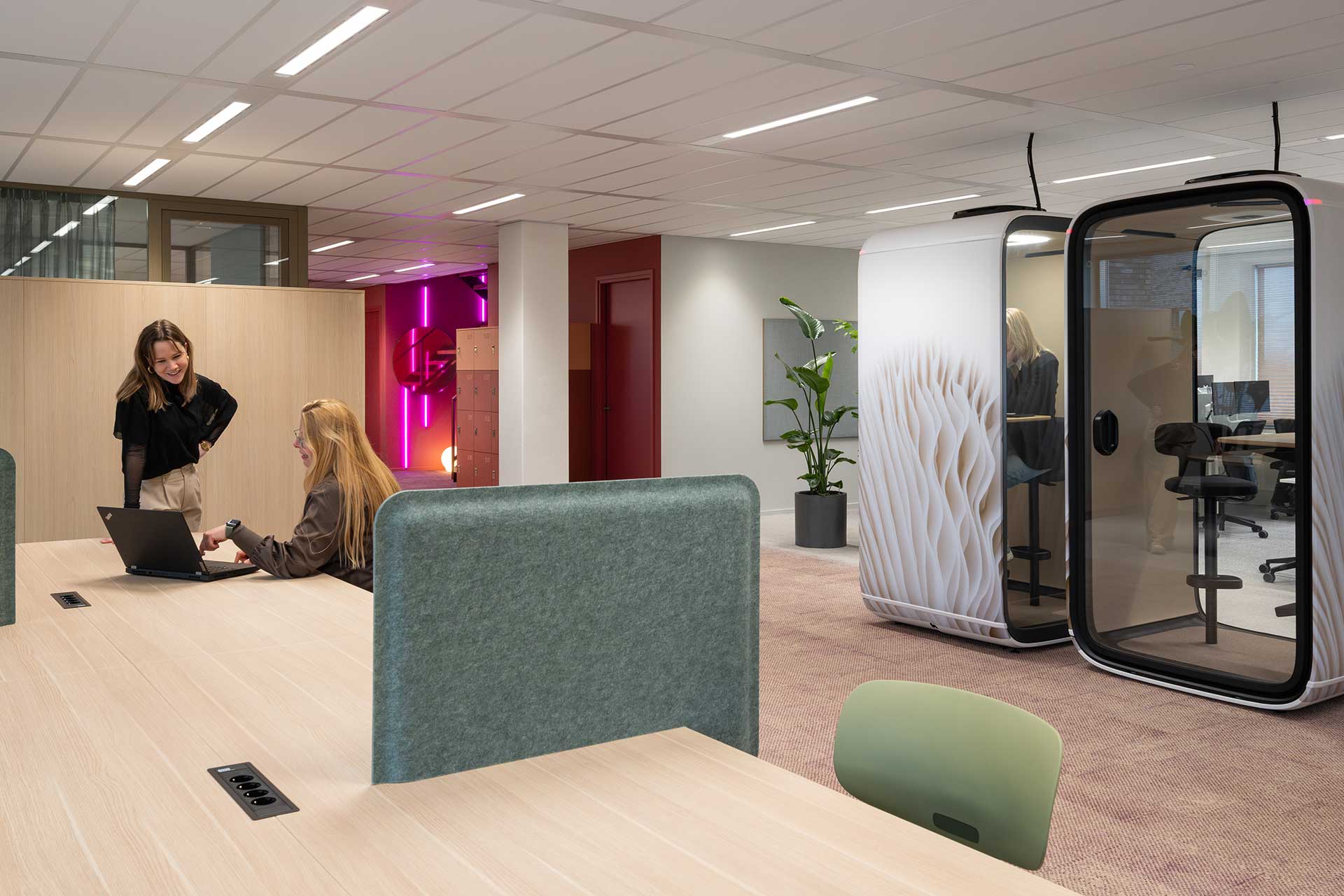 Modern office space with large work tables, meeting area, acoustic work pods and colourful LED accent lighting.