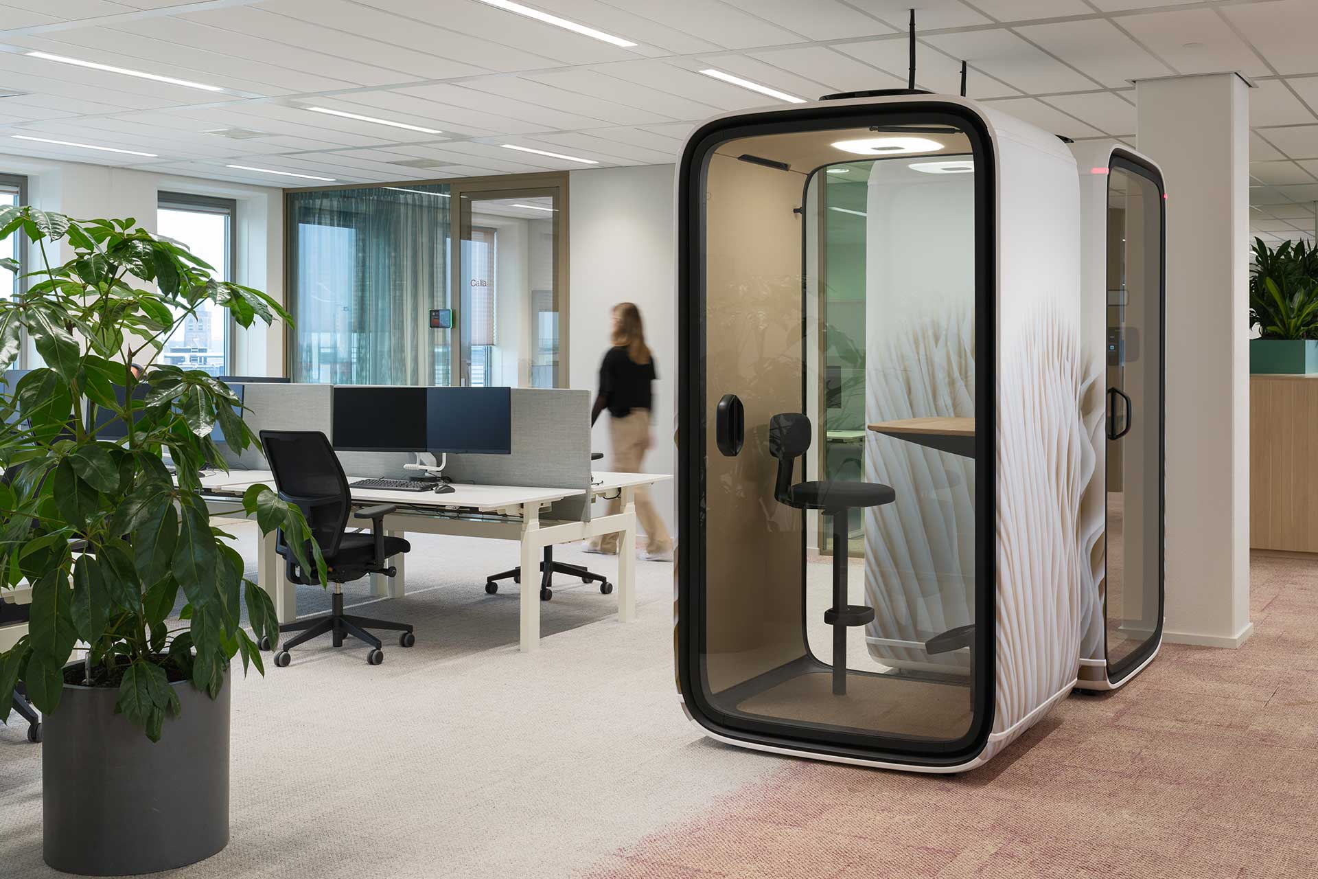 Modern office space with open workspaces, acoustic work pods, desk screens and plenty of natural light.