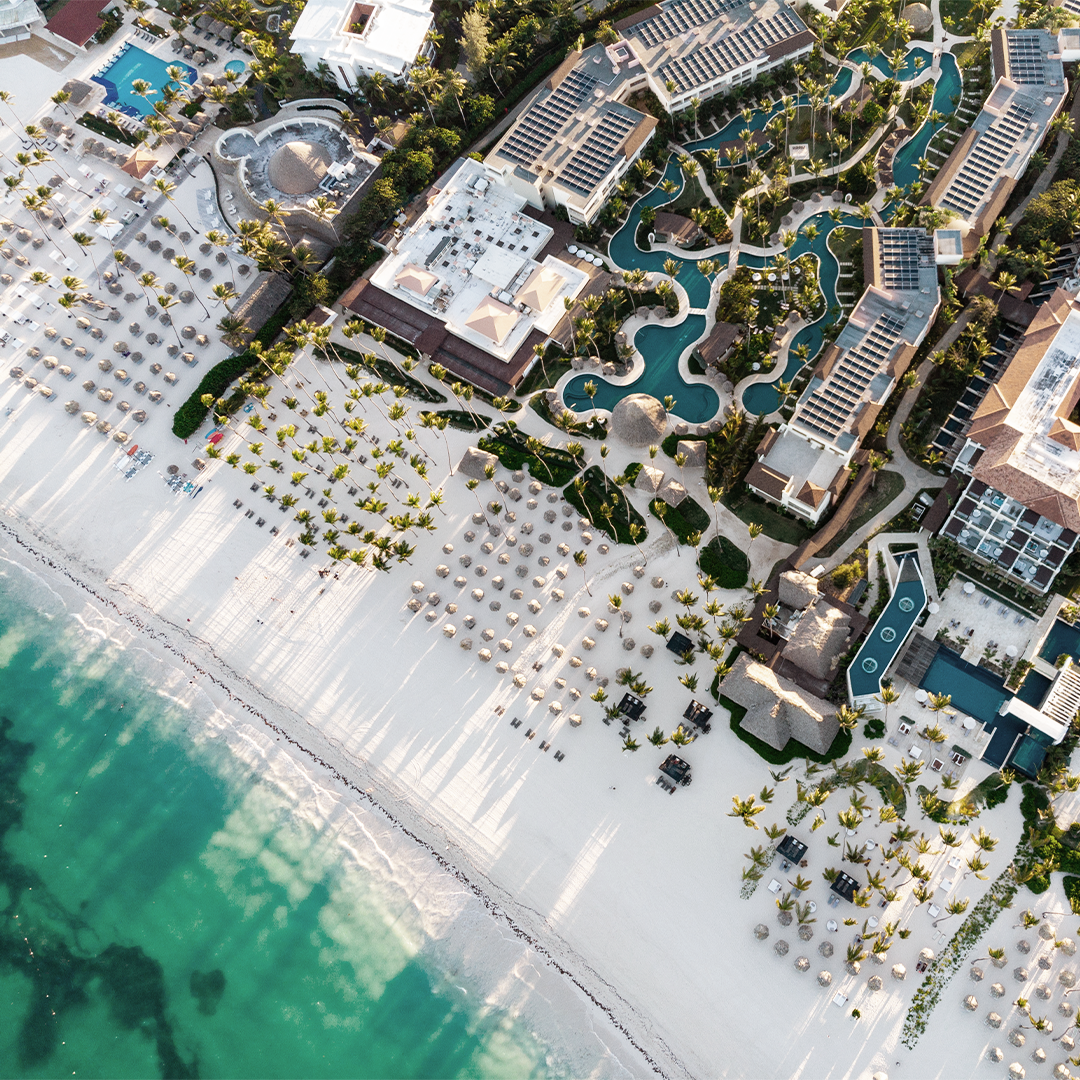 Aerial view of a luxury beachfront resort, showcasing pools, palm trees, and beach amenities. Ideal for hotel investment or tourism-related commercial development.