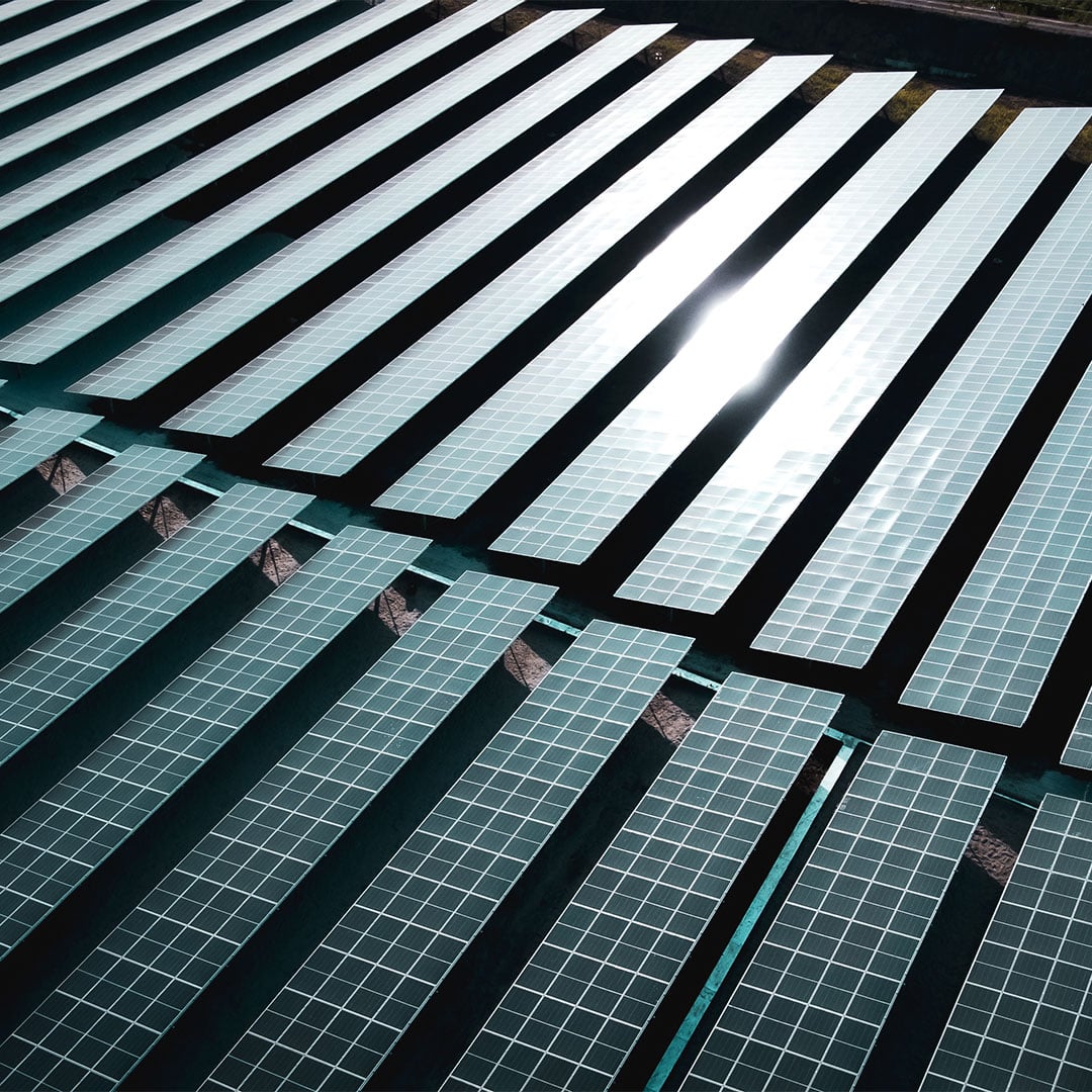 Aerial view of a large-scale community solar farm with rows of photovoltaic panels reflecting sunlight