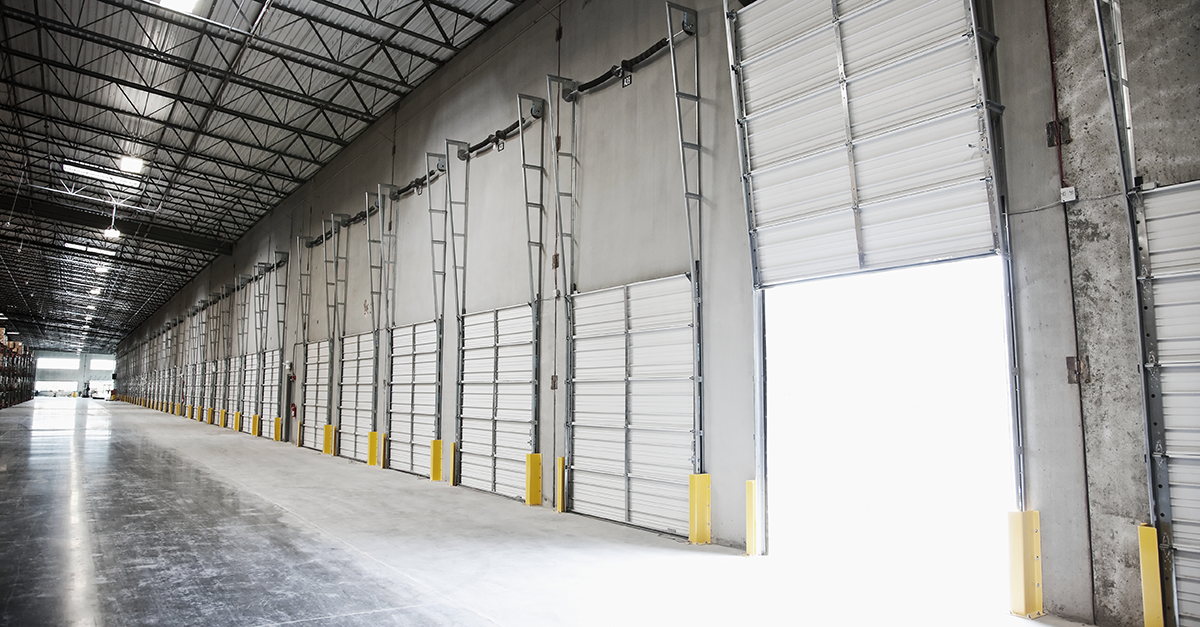 Interior view of a large warehouse featuring multiple loading docks and high ceilings, ideal for distribution or manufacturing businesses.