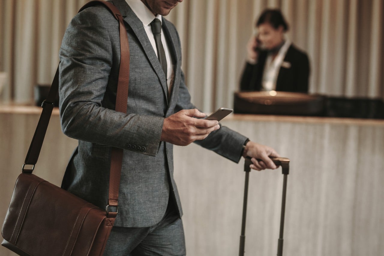 image of man walking through hotel lobby with suitcase